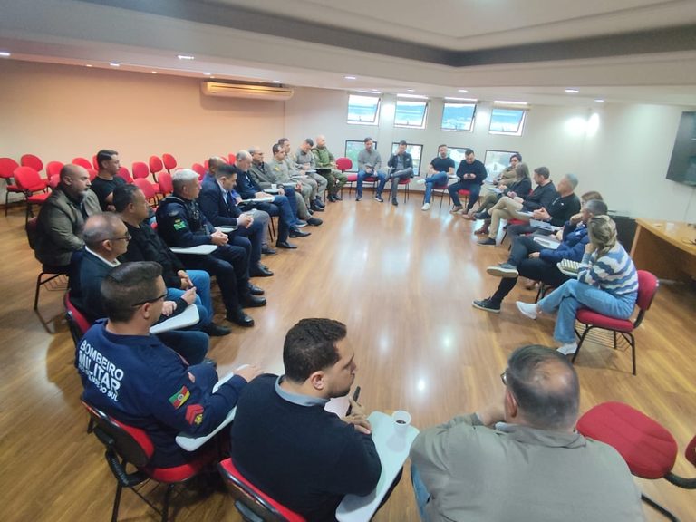 Vista geral da sala com autoridades, forças de segurança e empresários sentados em círculo na sede da ACIS