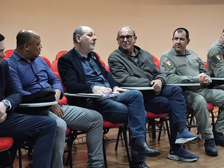 Autoridades e policiais militares sentados lado a lado durante a reunião na ACIS