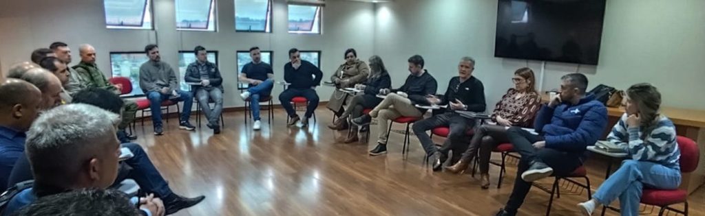 Autoridades e representantes das forças de segurança reunidos em círculo na sede da ACIS em Sapucaia do Sul