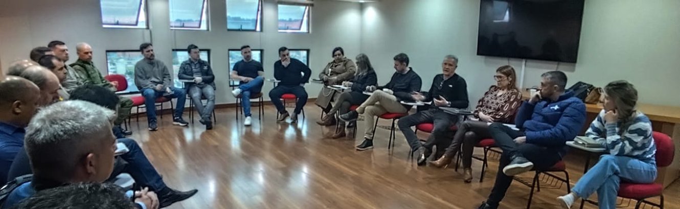 Autoridades e representantes das forças de segurança reunidos em círculo na sede da ACIS em Sapucaia do Sul
